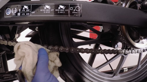 Hands removing excess lubricant on a motrocycle chain
