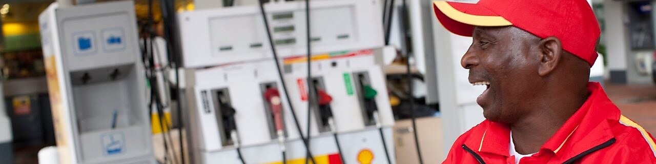 Forecourt attendant standing next to a pump